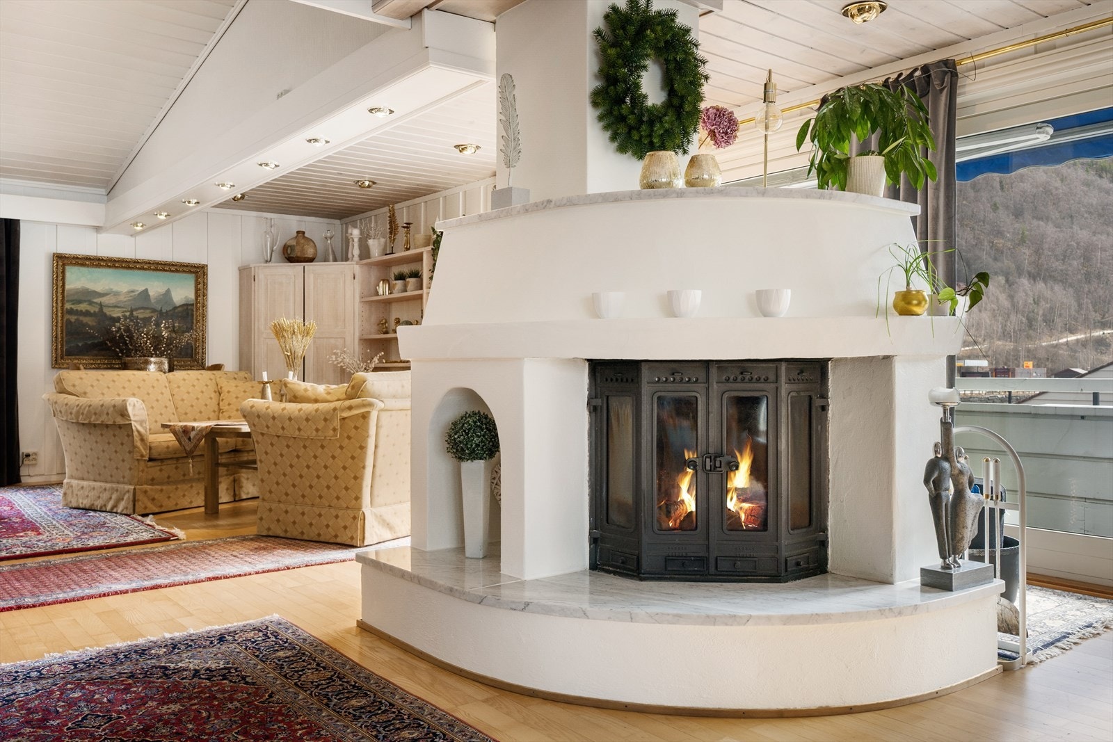 Den flotte peisen midt i rommet blir som en naturlig romdeler, og gjør det enkelt å møblere i flere soner. Galleribilde