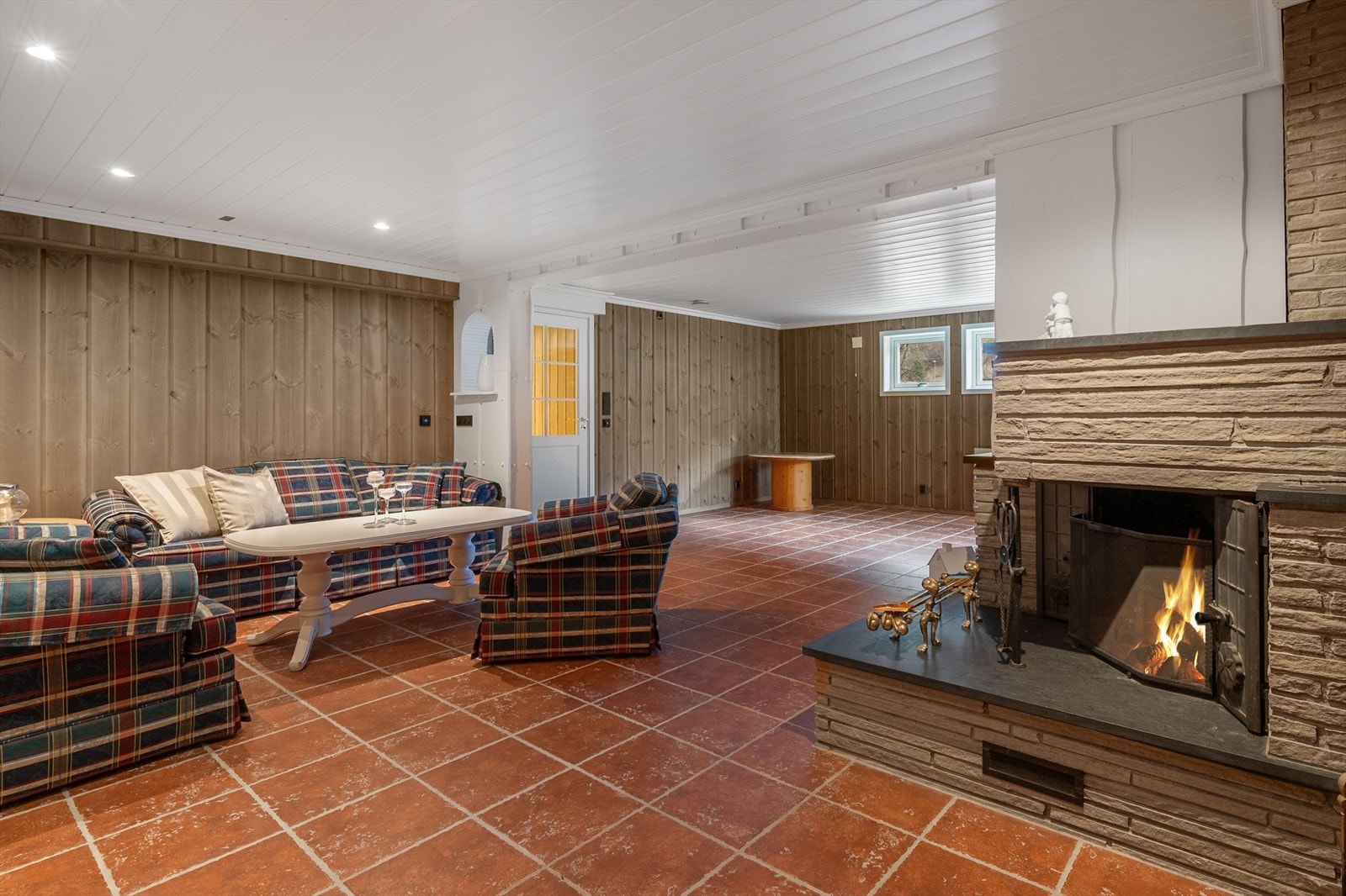 Beisede panelvegger og terracotta-fargede gulvfliser gjør at rommet blir lunt og hyggelig. Galleribilde