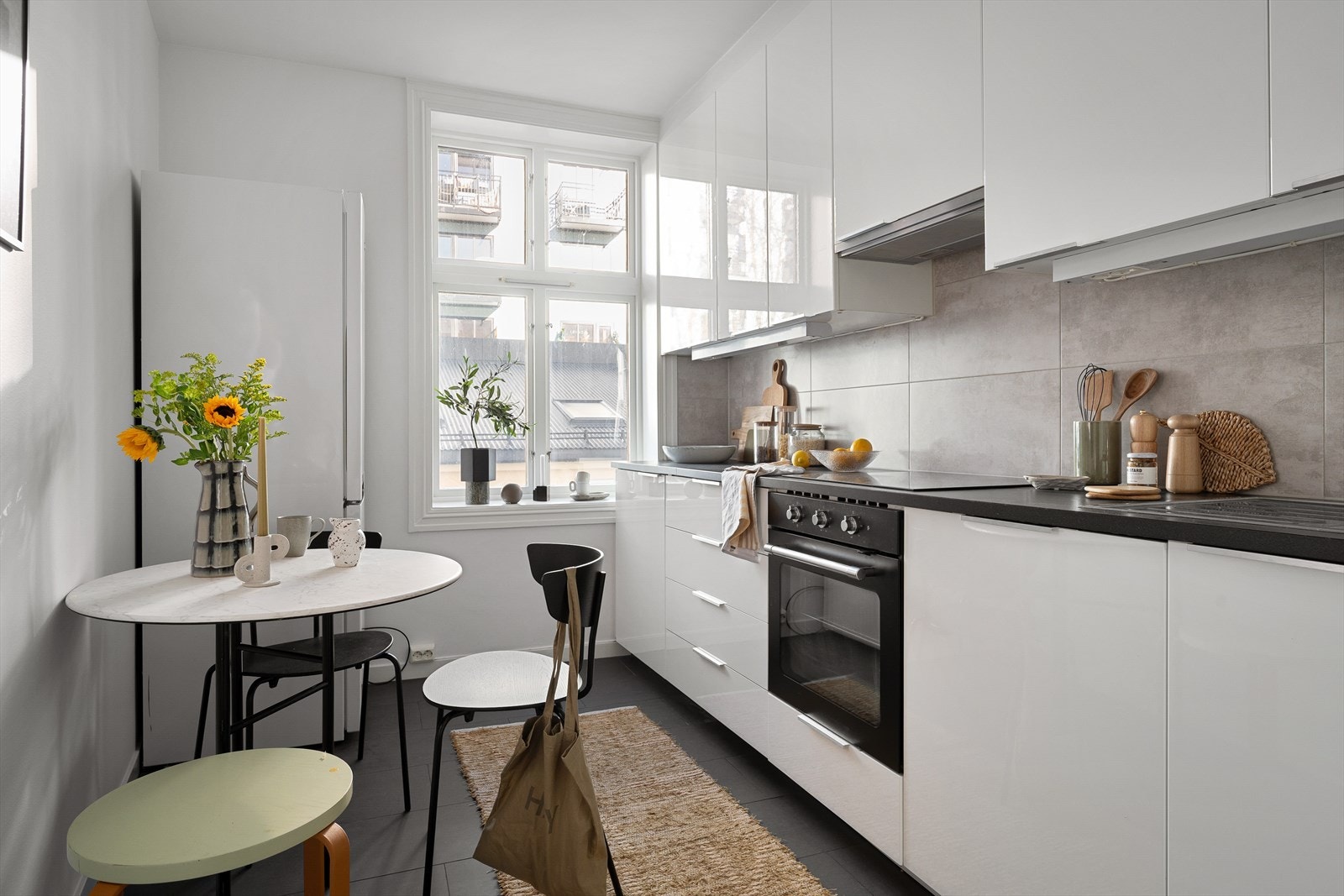 Tidløst kjøkken med en lekker kombinasjon av lyse, slette overflater, integrert grep og mørk benkeplate. Galleribilde