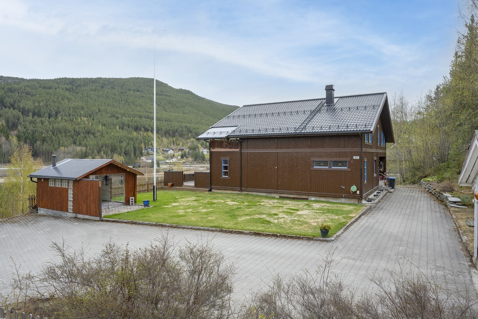 Tomten er opparbeidet med grøntarealer, belegningsstein, samt busker og trær. Galleribilde
