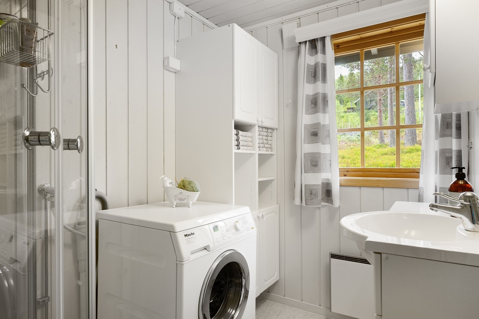 Badet er praktisk innredet med skapinnredning, overskap med speil/belysning, dusjkabinett samt opplegg for vaskemaskin. Galleribilde