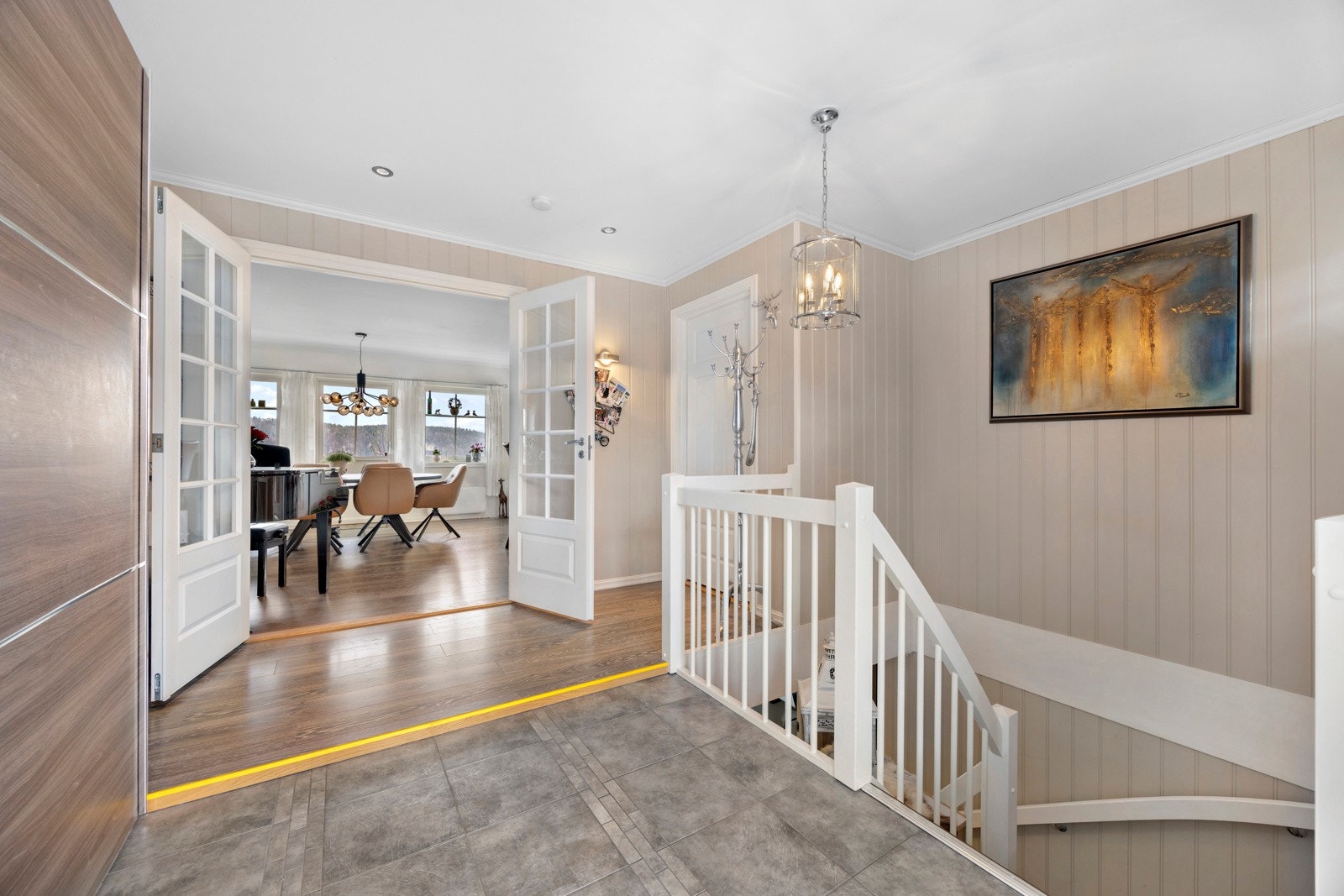 Gjennom tofløyede dører åpner boligens sosiale hjerte seg - en stor og luftig stue Galleribilde