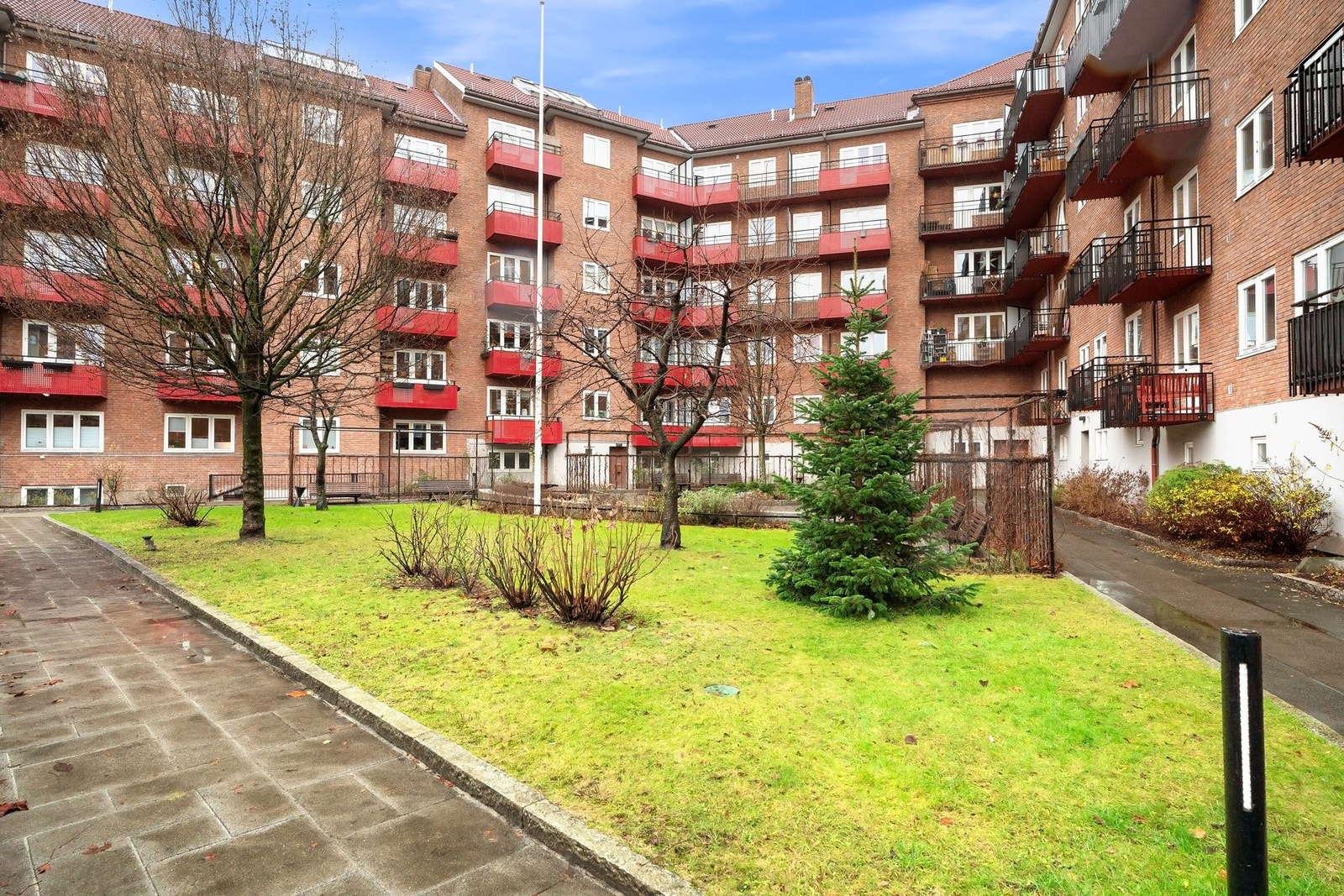 Pent opparbeidet gårdsrom, skjermet og solrikt med gressplener, frodig beplantning og hyggelige sittegrupper. Galleribilde