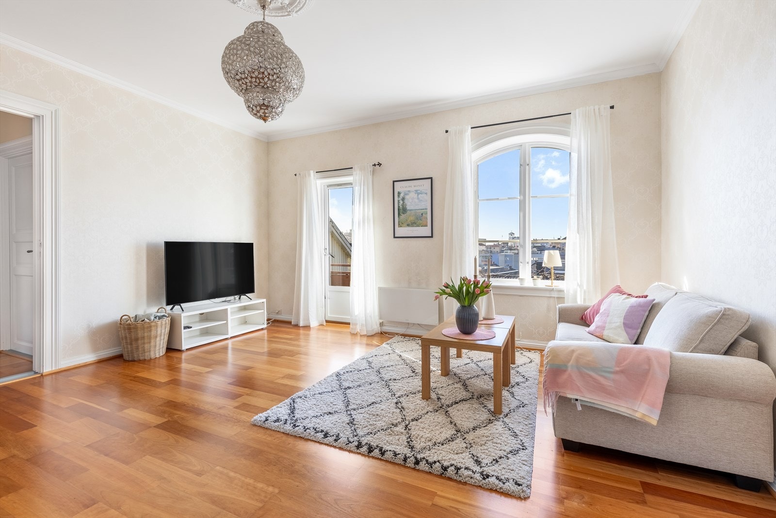 Stue med dør ut til solrik balkong med utsikt over byens tak Galleribilde