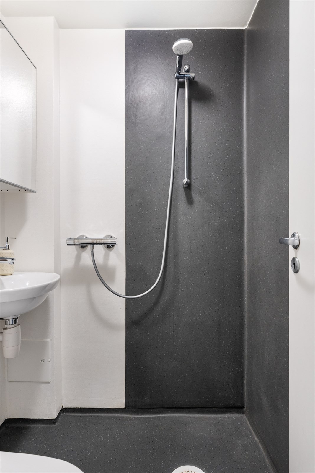 Badet består av dusj, gulvmontert toalett, speil og servant. Galleribilde