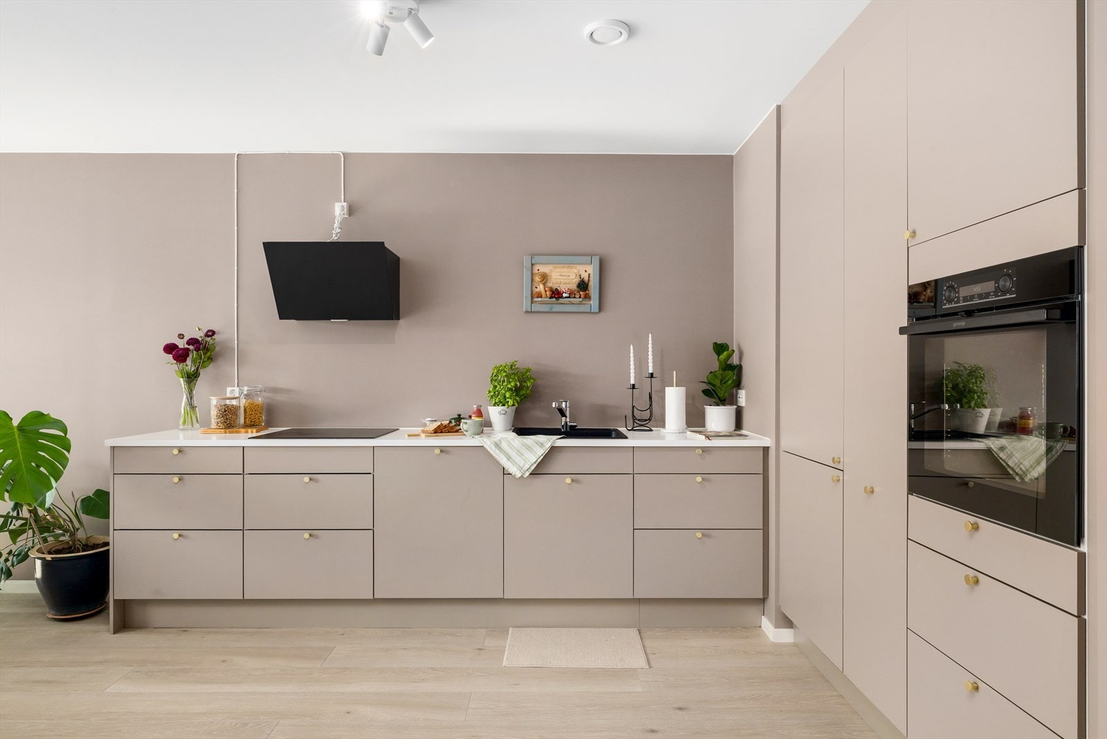 Kjøkkenet har et stilrent uttrykk i "L-form" fra Norema, med glatte fronter i en dempet gråtone som skaper et tidløst og sofistikert inntrykk Galleribilde