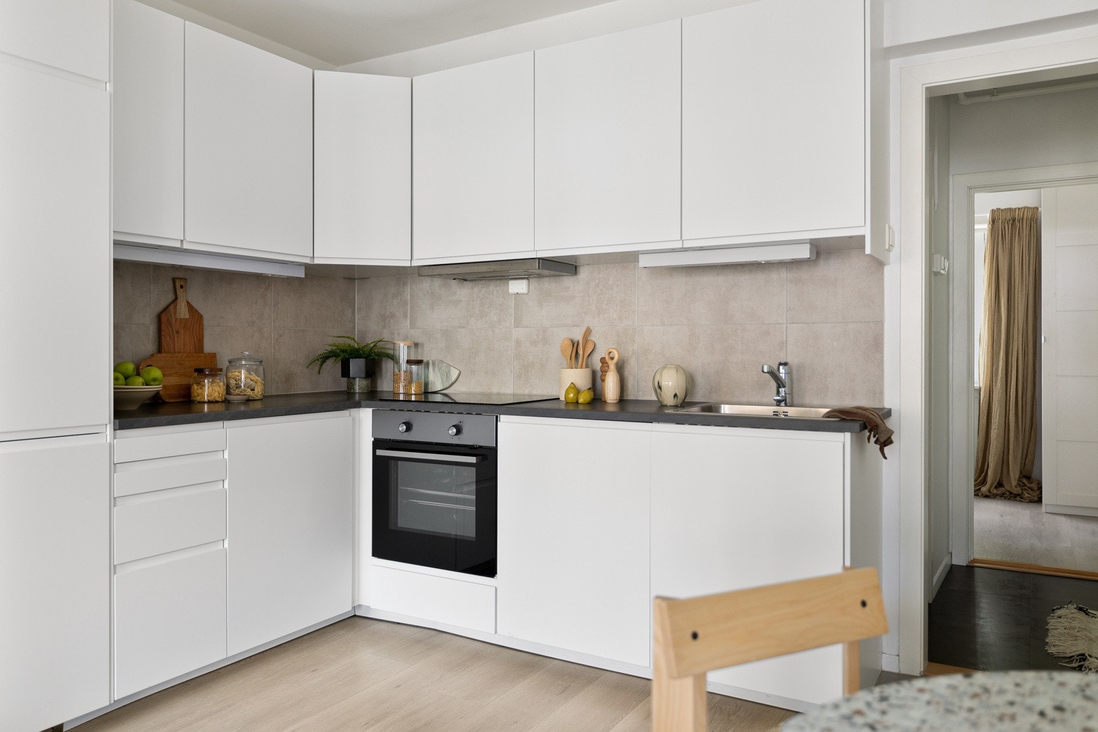 Kjøkkenet har en tidsriktig, glatt innredning fra IKEA med soft-close funksjon, kombinert med fliser over benk som gir et rent og moderne preg. Galleribilde