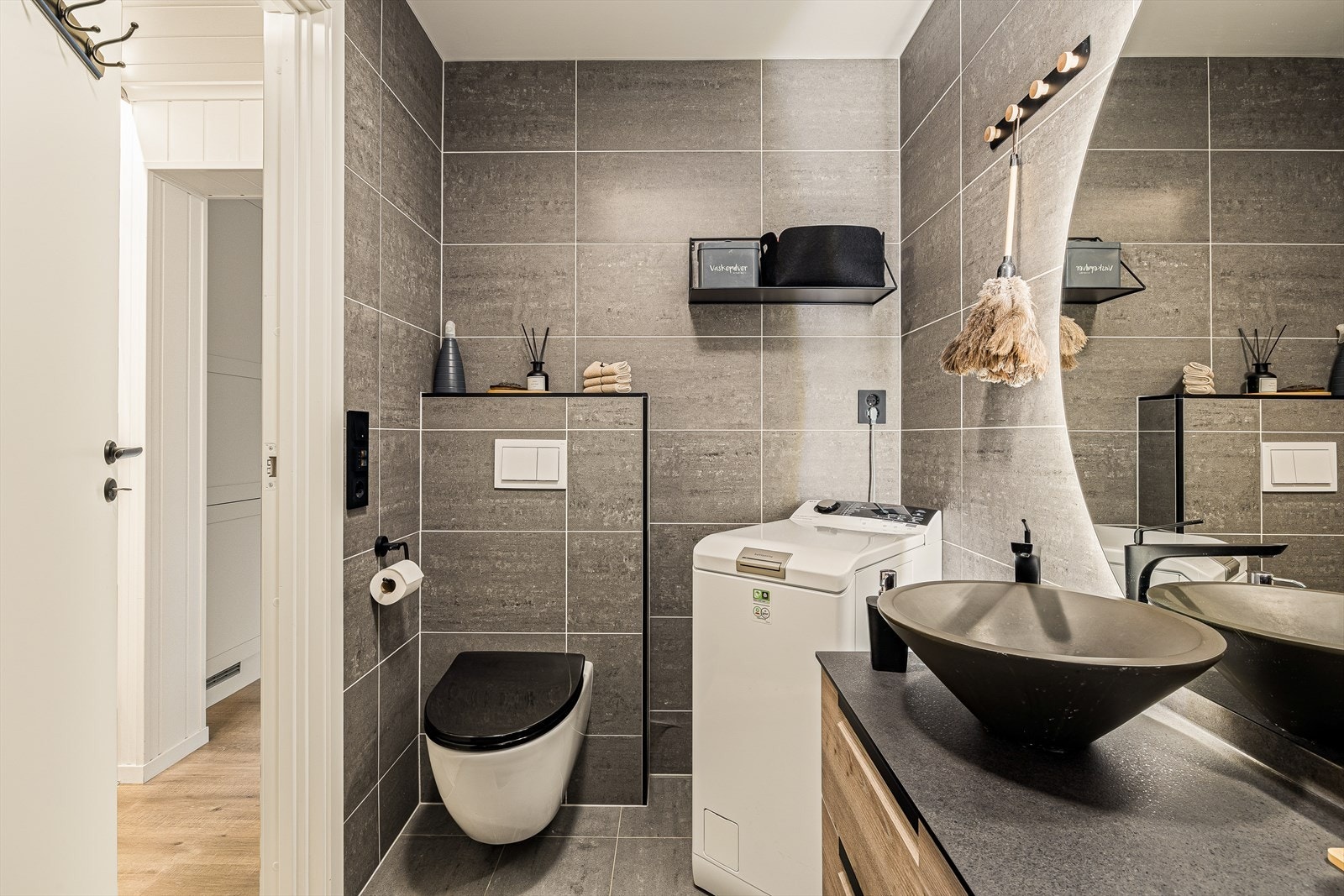 Rommet er innredet med servant med tilhørende underskap, veggmontert toalett, dujsvegger/hjørne, og opplegg for vaskemaskin. Galleribilde