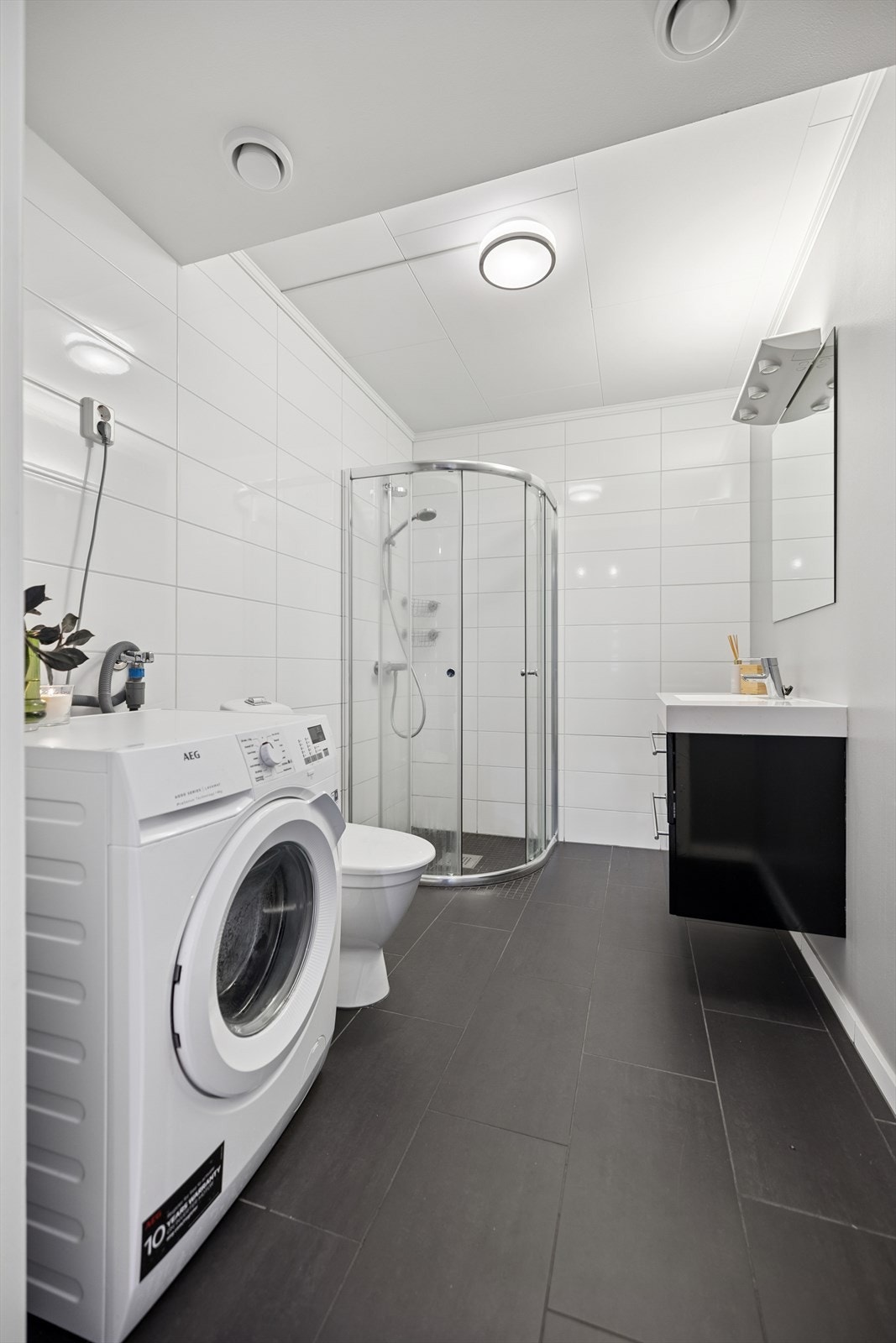 Her er det flislagt gulv med elektriske varmekabler og praktisk opplegg for vaskemaskin. Galleribilde