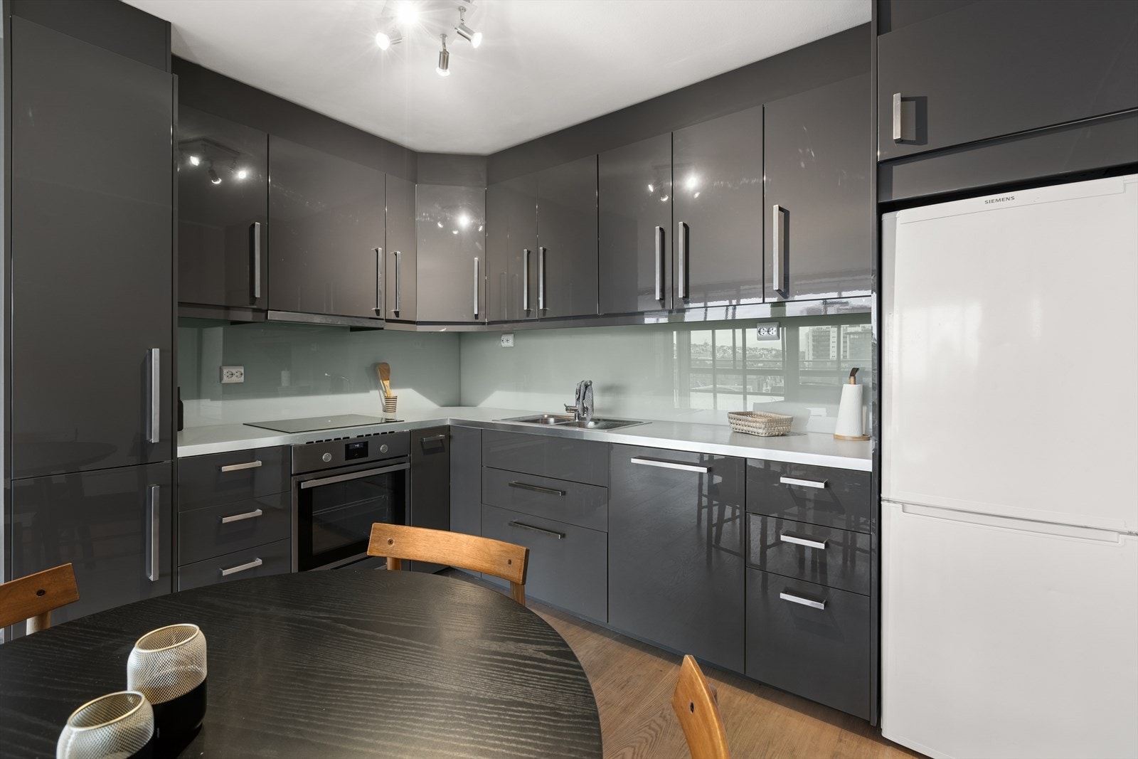 Innredningen har slette fronter, benkeplate i laminat og en glassplate mellom benken og overskapene. Galleribilde