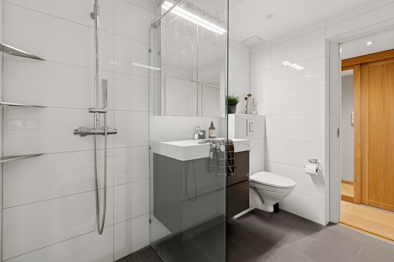 Innredningen består av servant med seksjon, dusjhjørne med glassvegger, vegghengt toalett og opplegg for vaskemaskin. Galleribilde