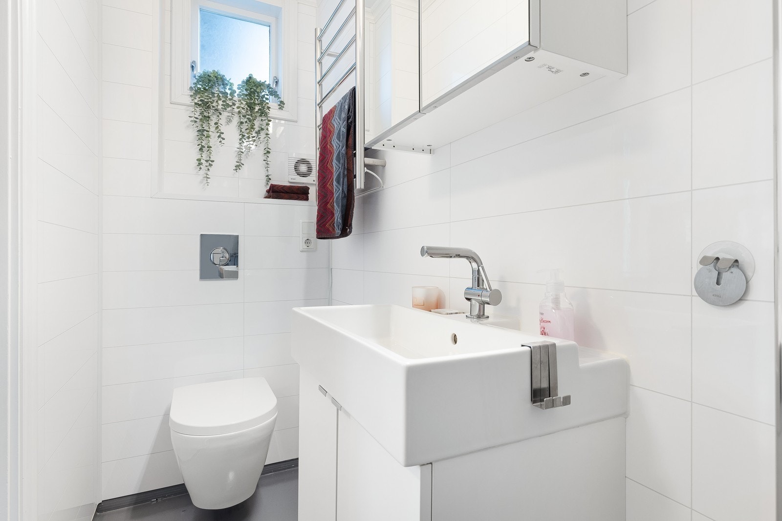 Baderom med vegghengt toalett, baderomsmøbel med servant og dusjhjørne. Galleribilde