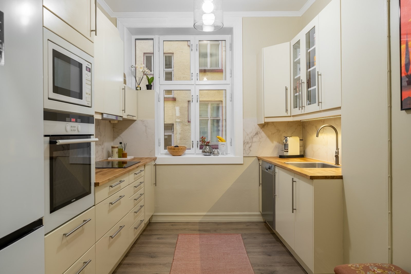 Lys og pen kjøkkeninnredning med slette fronter og god skap- og benkeplass Galleribilde