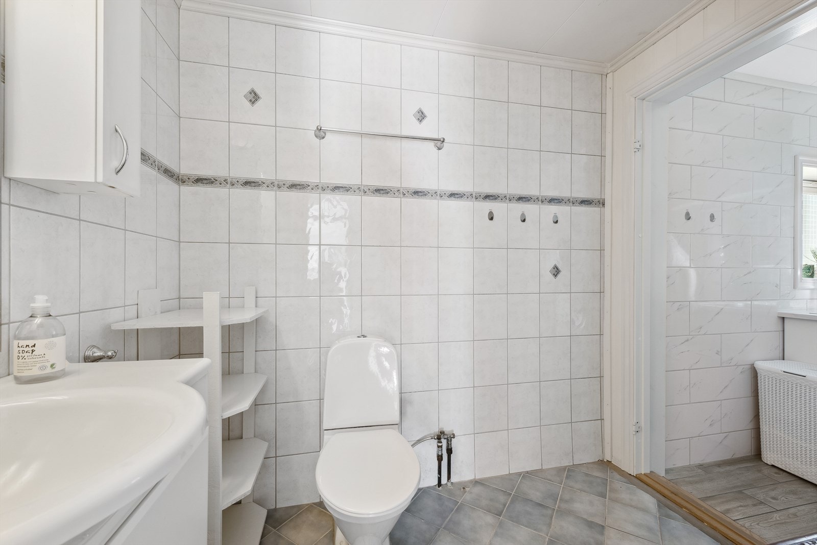 Flislagt bad med håndvask og gulvmontert klosett. Galleribilde