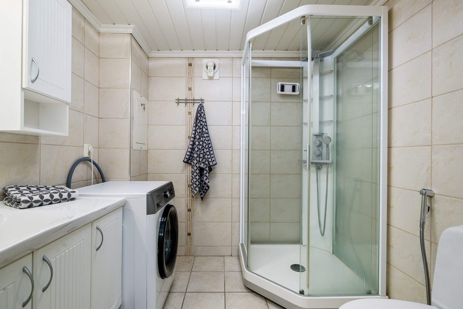 Bad/vaskerom m/innredning med nedfelt servant, speil, veggskap, kabinett, klosett og opplegg til vaskemaskin Galleribilde