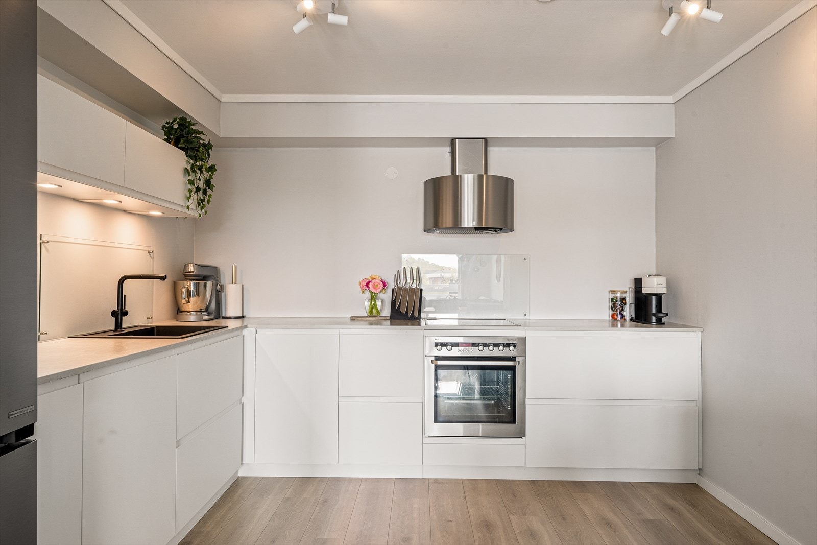 Kjøkkenet har innredning med glatte fronter og laminert benkeplate med nedfelt kum. Integrert steketopp, komfyr og oppvaskmaskin. Galleribilde