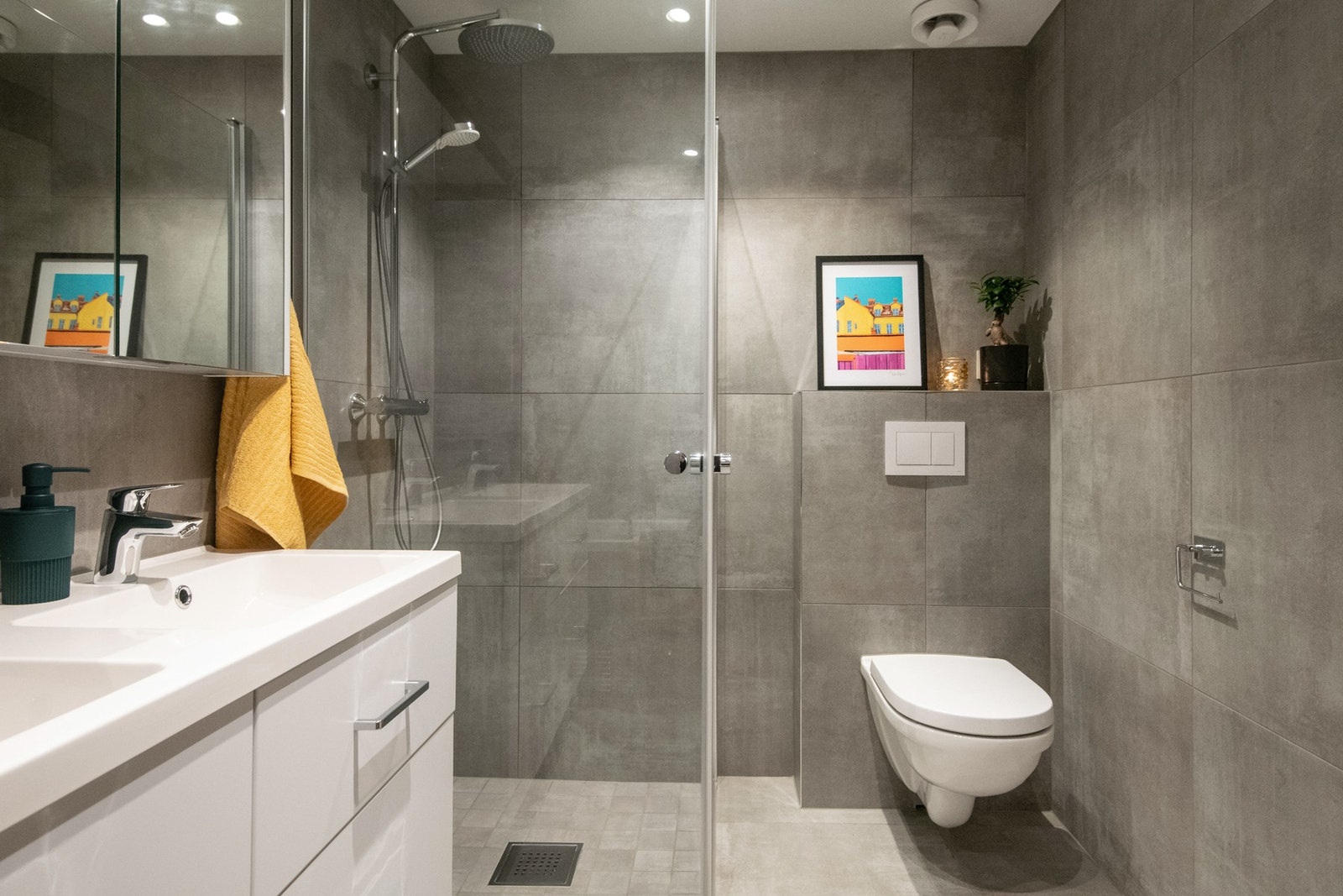 Baderomsinnredningen består av både benkeskap og veggskap med glatte fronter, og det vegghengte toalettet med innebygget sisterne gir rommet et rent og moderne uttrykk. Galleribilde