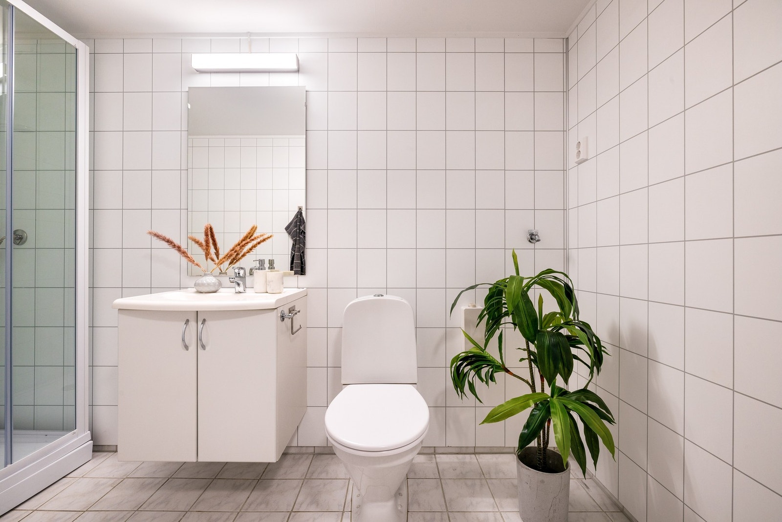 Badet lyst med fliser på gulv og baderomsplater på vegg. Galleribilde