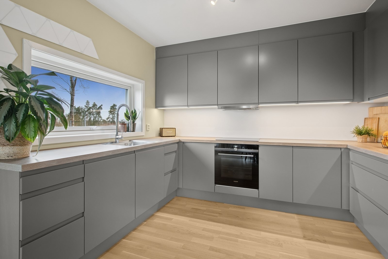 Delikat kjøkkeninnredning med godt om skap- og benkeplass. Galleribilde