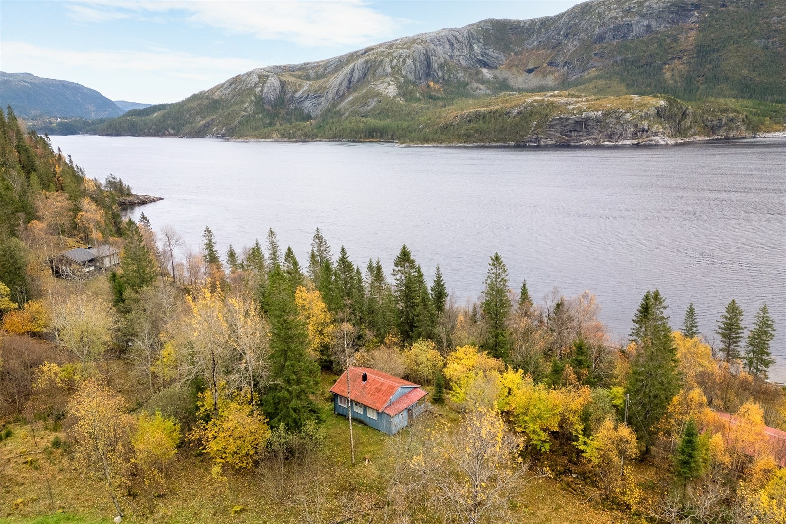Fritidsboligen har en naturskjønn beliggenhet med utsikt mot fjorden, omgitt av frodig vegetasjon. Galleribilde