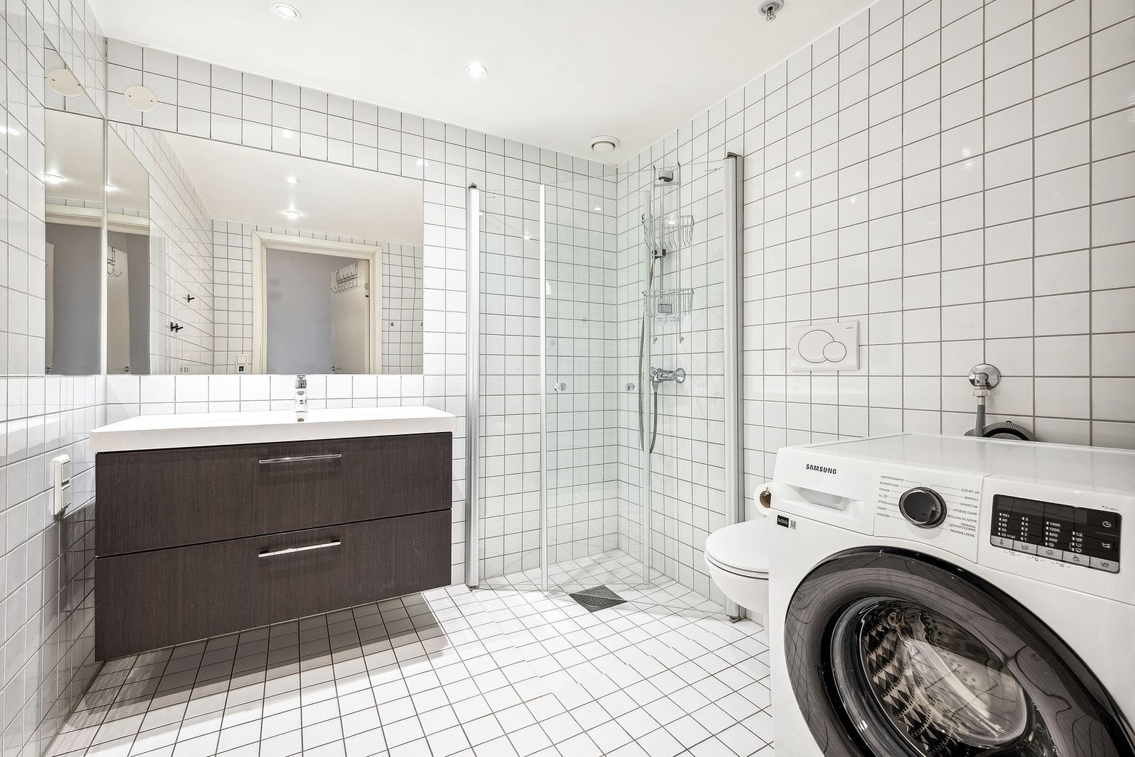 Flislagt bad med varme i gulv, servant, wc og dusjnisje samt vaskemaskin. Galleribilde