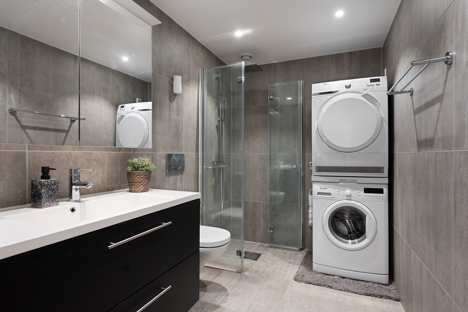 Badet er helfliset og utstyrt med dusjhjørne, vegghengt toalett og opplegg for vaskemaskin. Galleribilde