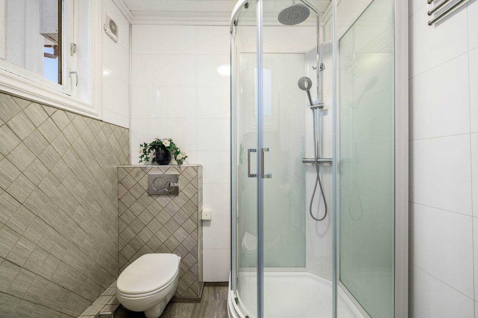 Bad med vegghengt toalett, baderomsinnredning i nedfelt servant og dusjkabinett. Galleribilde