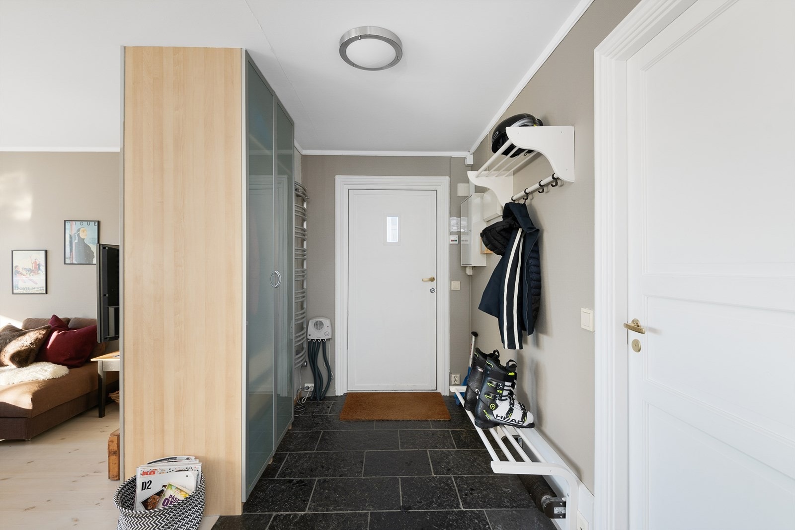 Lys entré med romslig garderobe med plass for å henge av seg yttertøy. Steinflis på gulv med varmekabler. Galleribilde