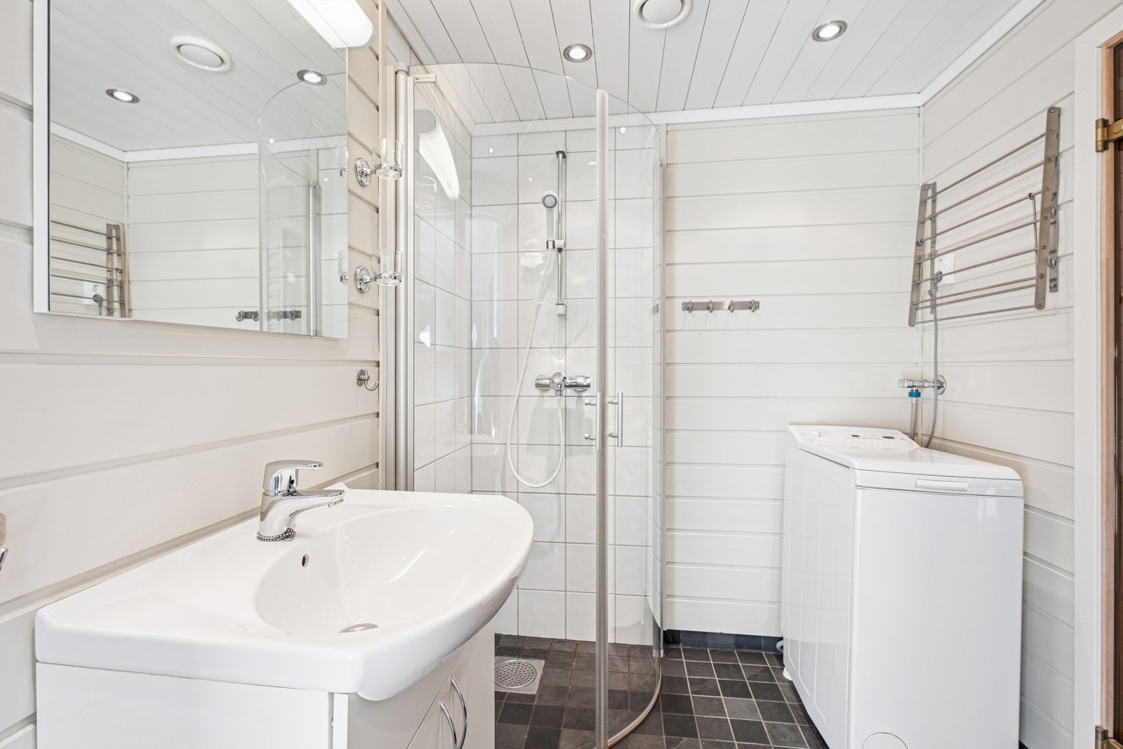 Badet er utstyrt med servant, dusjhjørne og opplegg for vaskemaskin. Her er det varme i gulvet. Galleribilde