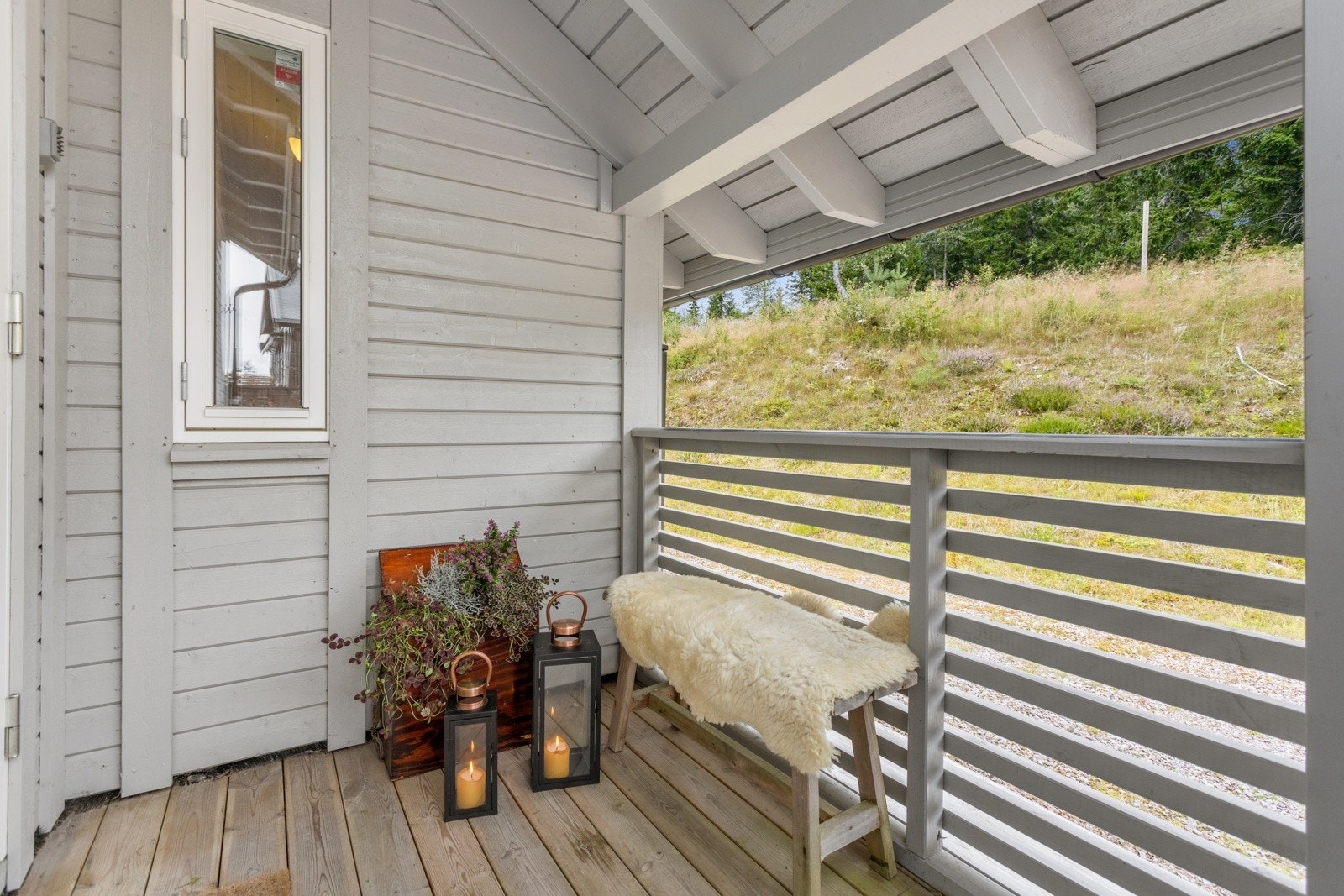 Hytta har overbygd inngangsparti som skjermer mot vær og vind. Her ute er det rom for utepynt og benk Galleribilde