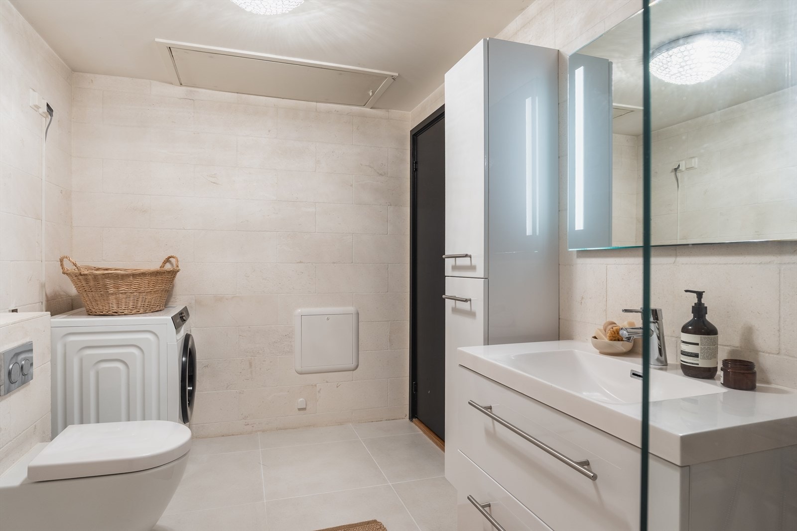 Rommet er innredet med servant nedfelt i baderomsinnredning, vegghengt toalett, innfliset badekar og praktisk opplegg for vaskemaskin. Galleribilde