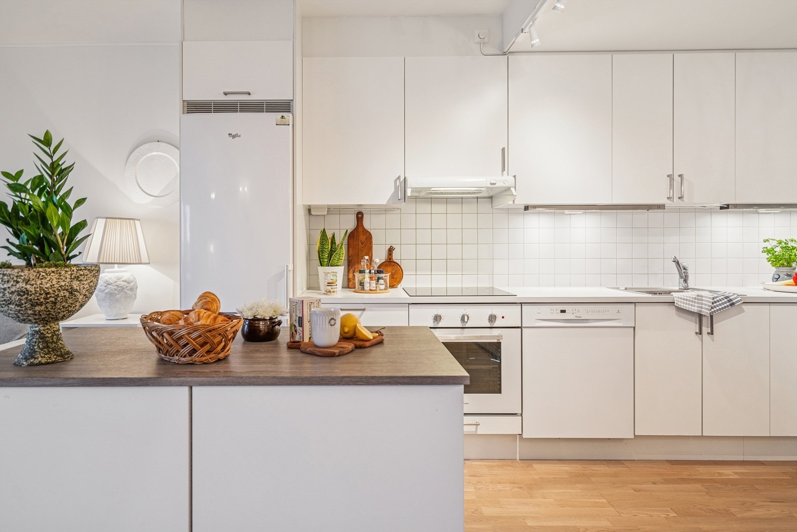 Pent sigdal kjøkken med glatte fronter og en kjøkkenøy. Benkeplaten er i laminat med en nedfelt vaskekum. Galleribilde