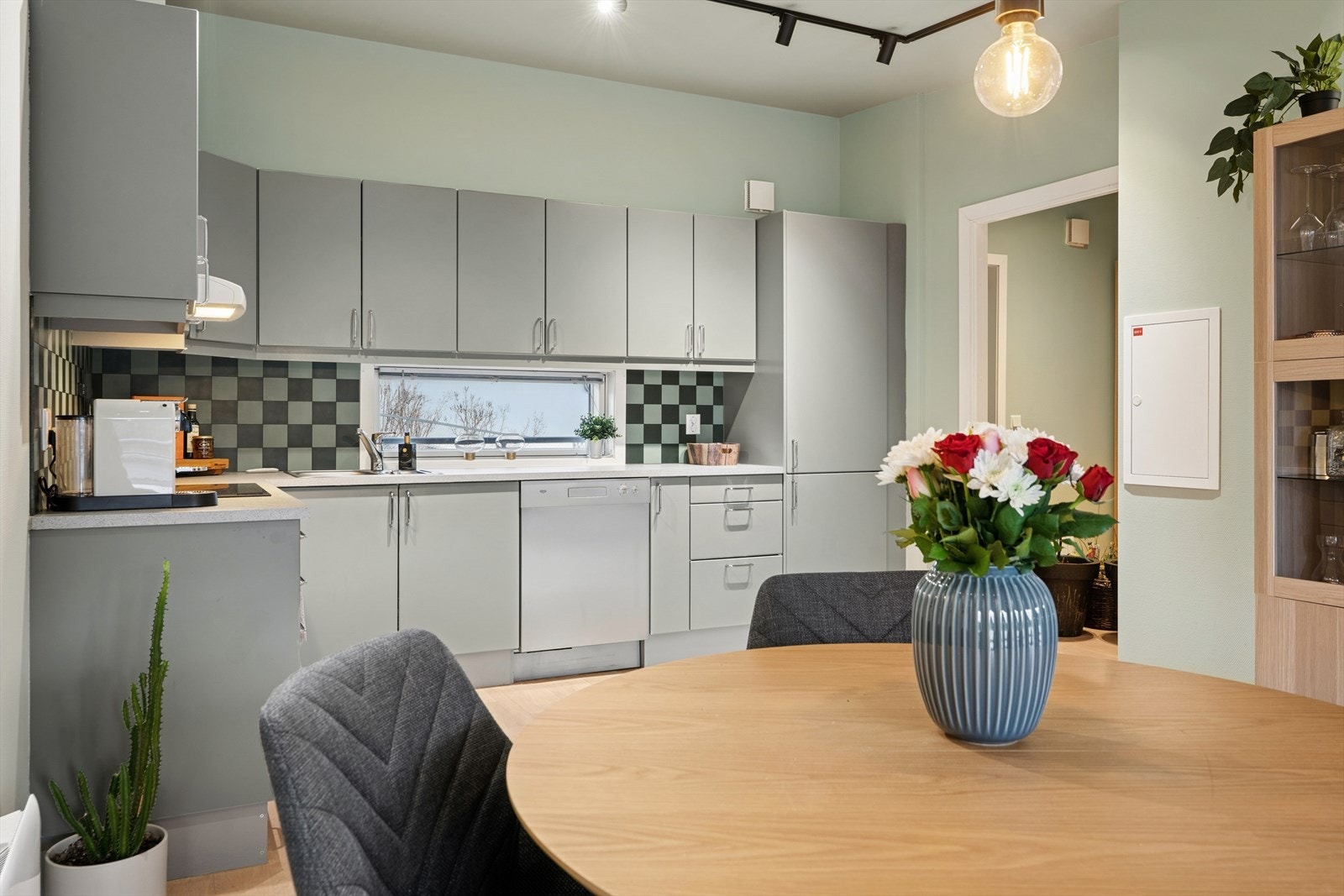 En moderne og funksjonell vinkelløsning med glatte fronter, laminat benkeplate, oppvaskkum med ettgreps blandebatteri og ventilator over kokesonen Galleribilde