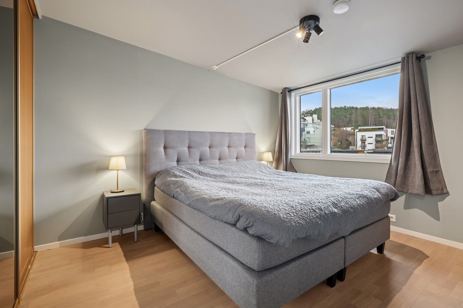 Soverommet har god plass til dobbeltseng og nattbord, og fremstår lunt med parkettgulv og nøytrale farger på veggene Galleribilde