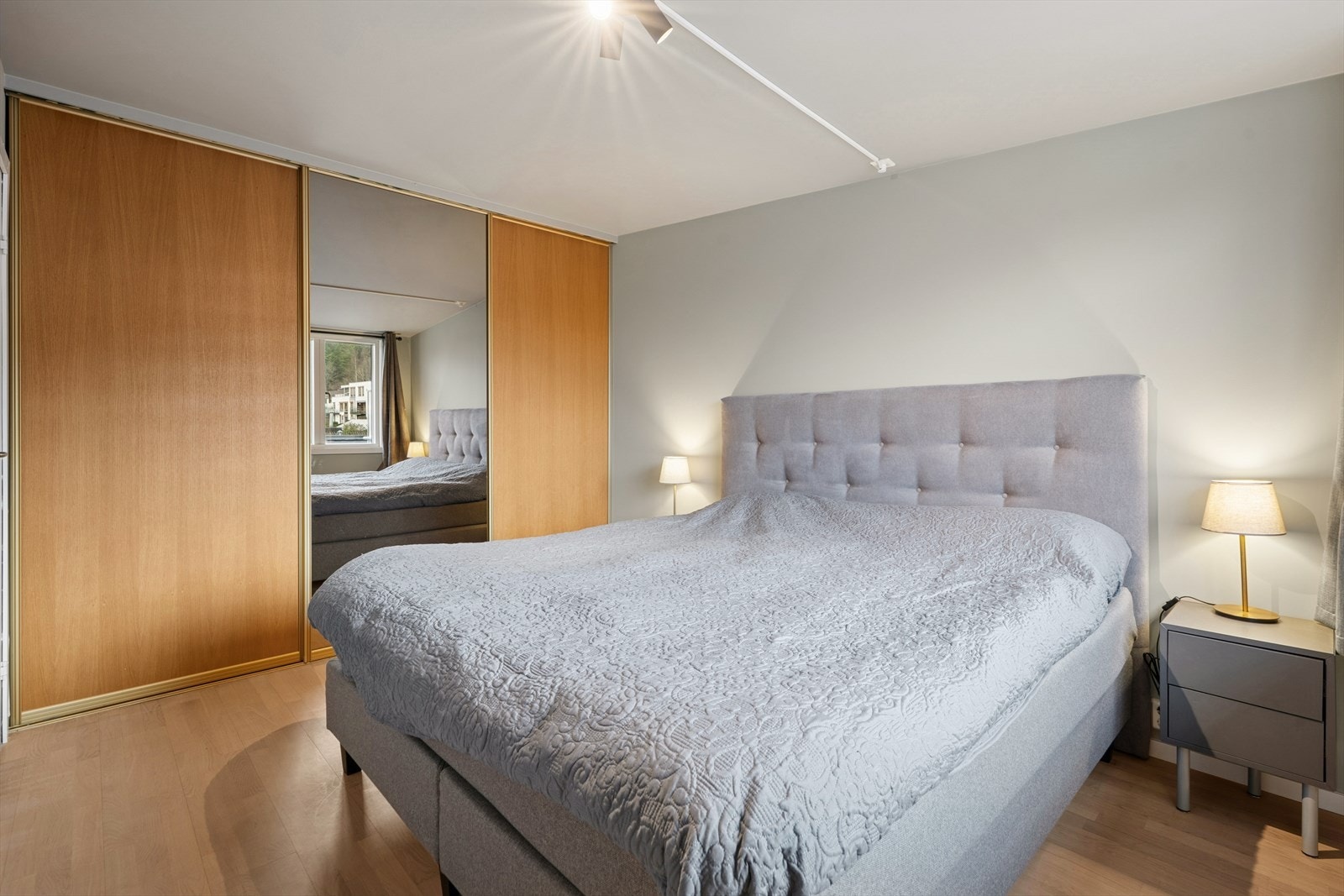 Soverommet har en skyvedørsgarderobe med glatte fronter i eik og speil som gir rikelig med oppbevaringsplass for klær og sko Galleribilde