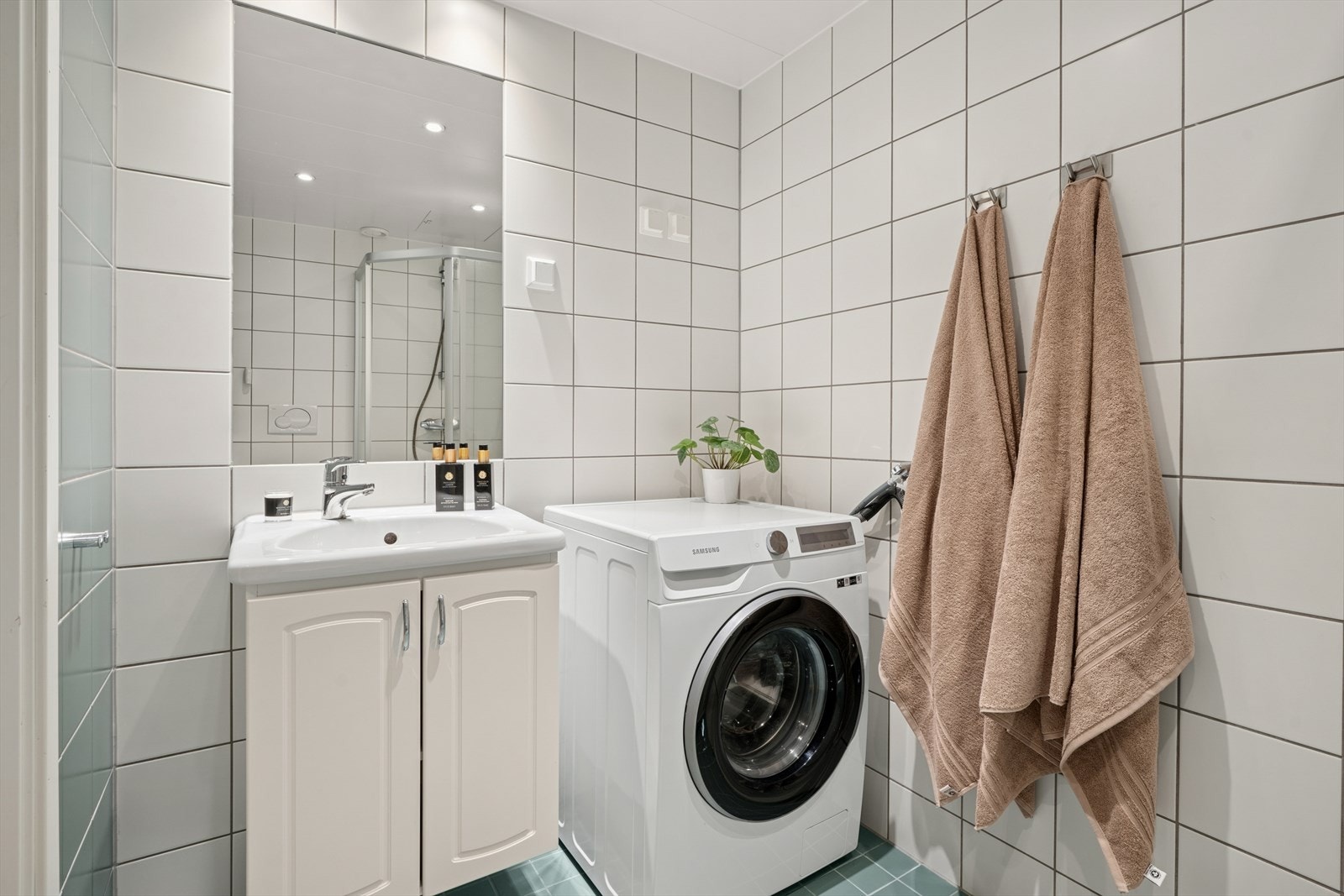 Badet har flislagte overflater med hvite veggfliser og grå gulvfliser. Gulvet er utstyrt med elektriske varmekabler for god komfort Galleribilde