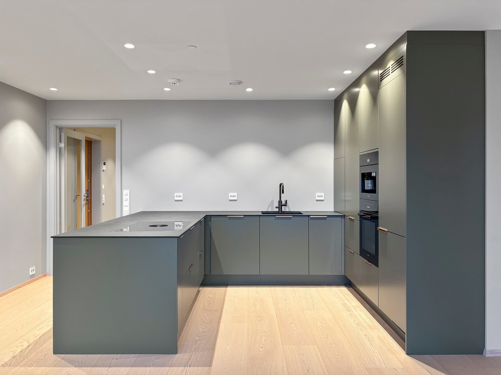 Kjøkkenet har slette fronter og moderne håndtak i børstet gull. Galleribilde