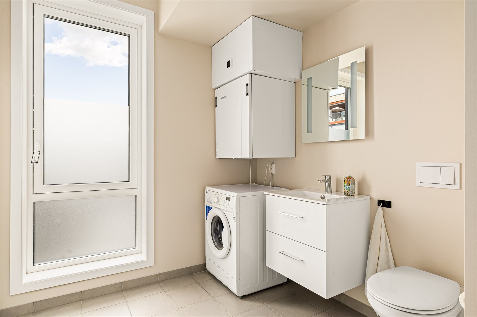 Praktisk og plassbygget vaskerom med gjennomtenkte løsninger som gjør hverdagen enklere. Rommet har flislagt gulv med vannbåren gulvvarme som sørger for god komfort året rundt. Galleribilde