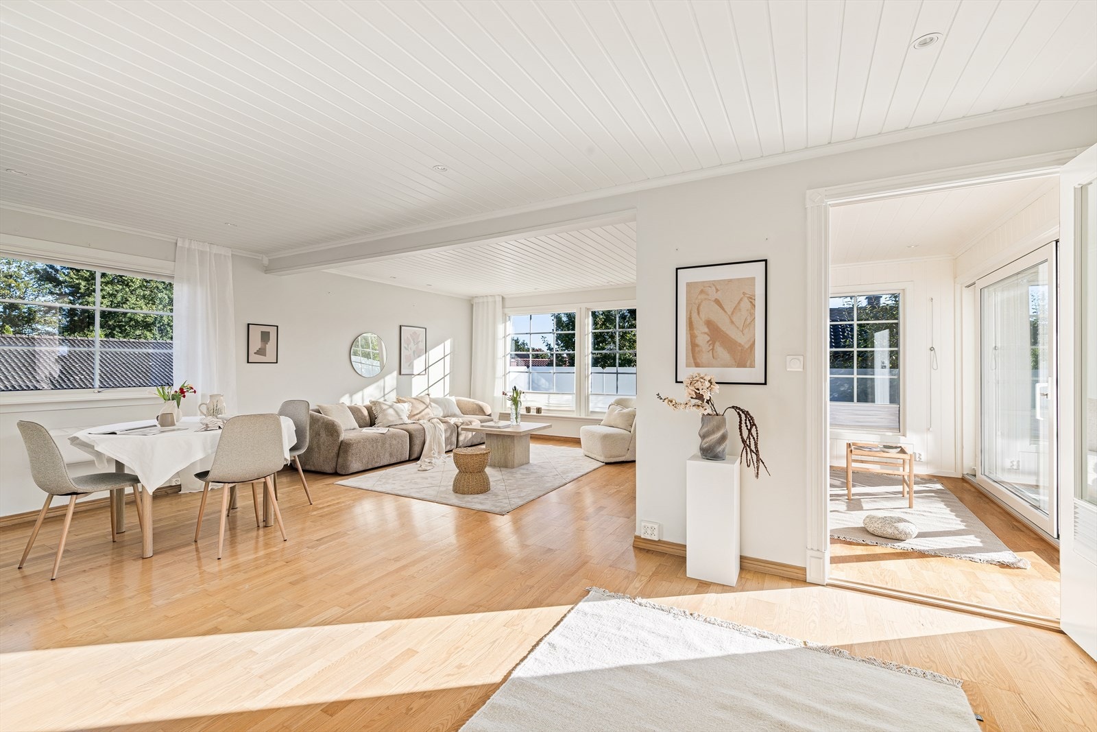 Tilbygget rom til høyre i bildet gir boligen ekstra fleksibilitet - med direkte utgang til en romslig og solrik terrasse, perfekt for avslapping, sosiale sammenkomster eller som en forlengelse av oppholdsrommet. Galleribilde