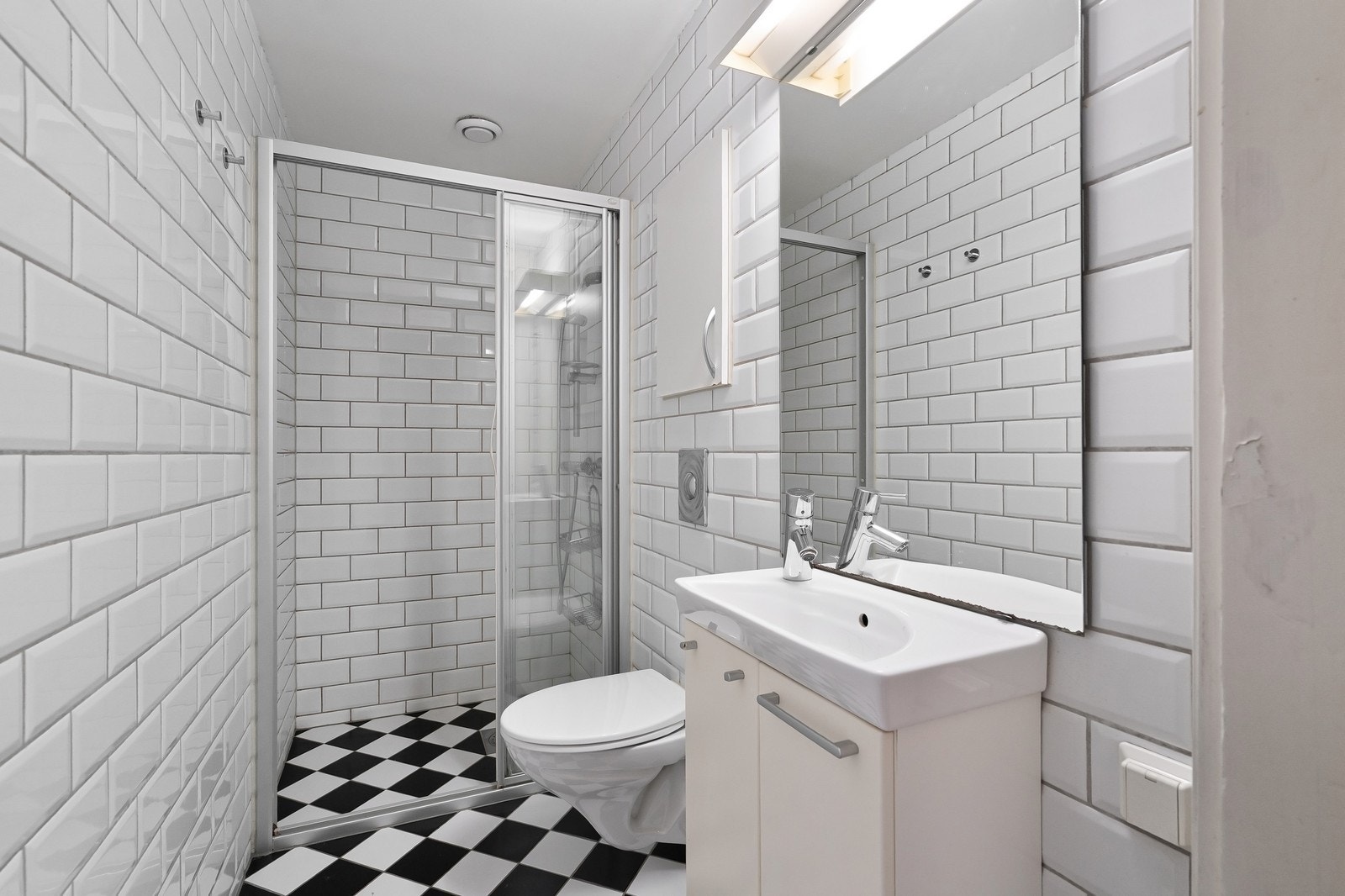 Moderne, flislagt bad med dusjhjørne, vegghengt toalett og gulvvarme – praktisk og stilrent. Galleribilde