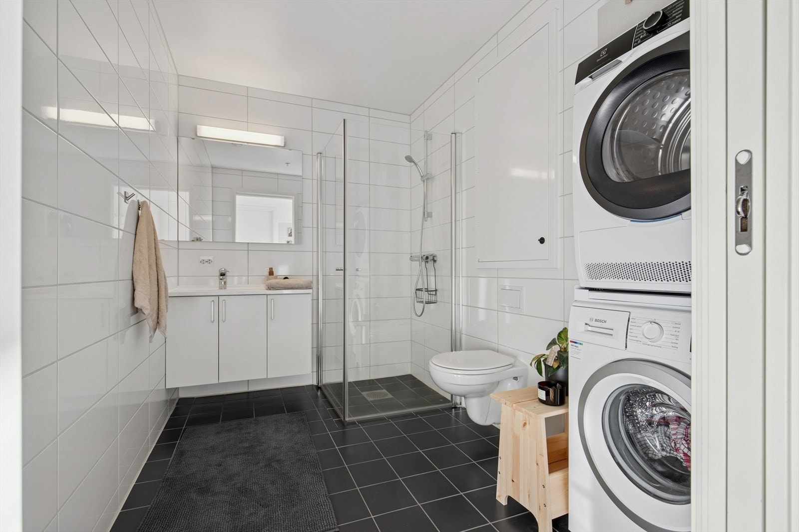 Badet er stilrent med tidløs baderomsinnredning, vegghengt toalett og dusjhjørne. Her er det naturligvis opplegg for både vaskemaskin og tørketrommel og gulvvarme. Galleribilde