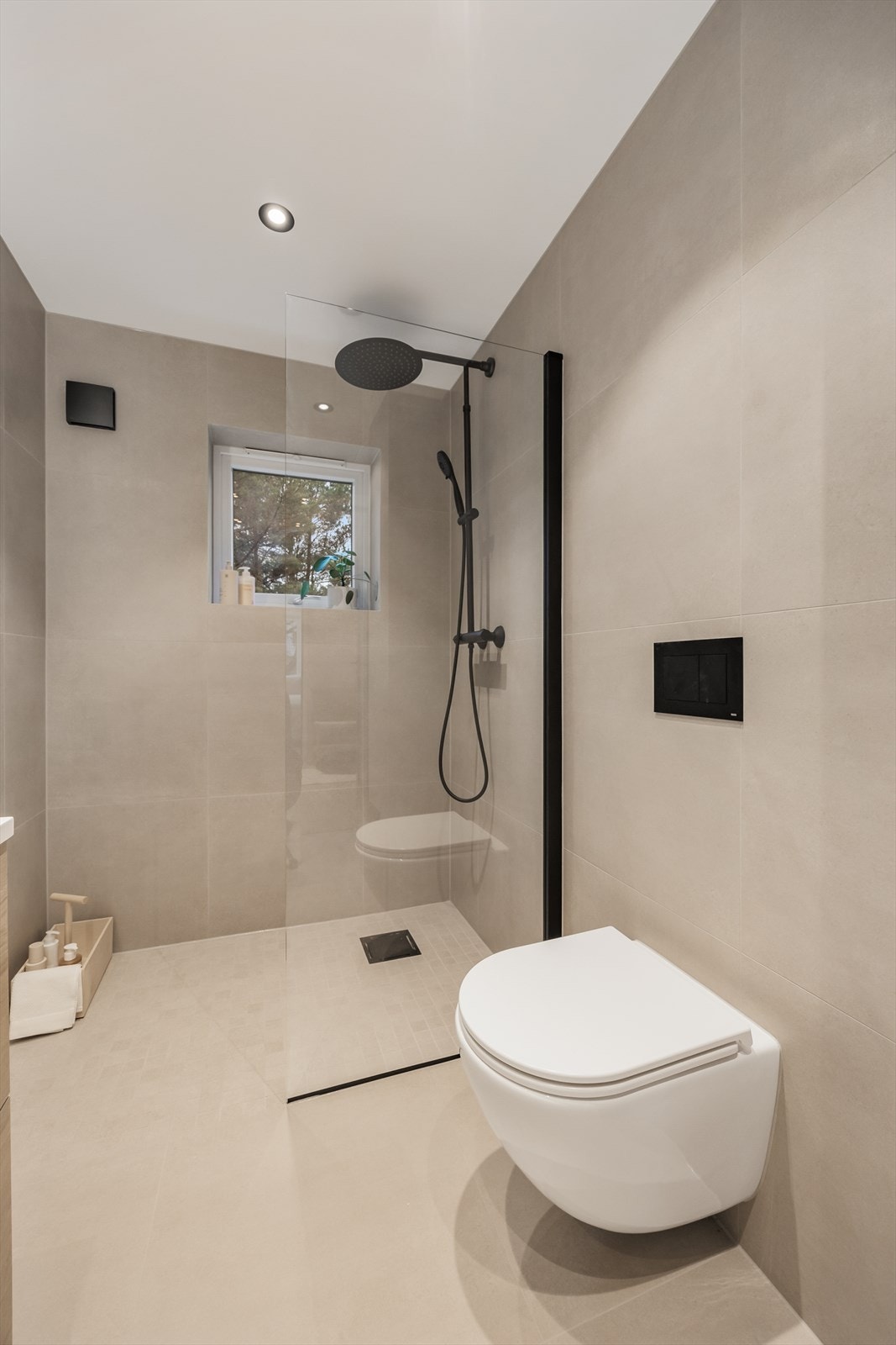 Rommet har et dusjhjørne med nedsenket gulv, vegghengt toalett og opplegg for vaskemaskin. Galleribilde