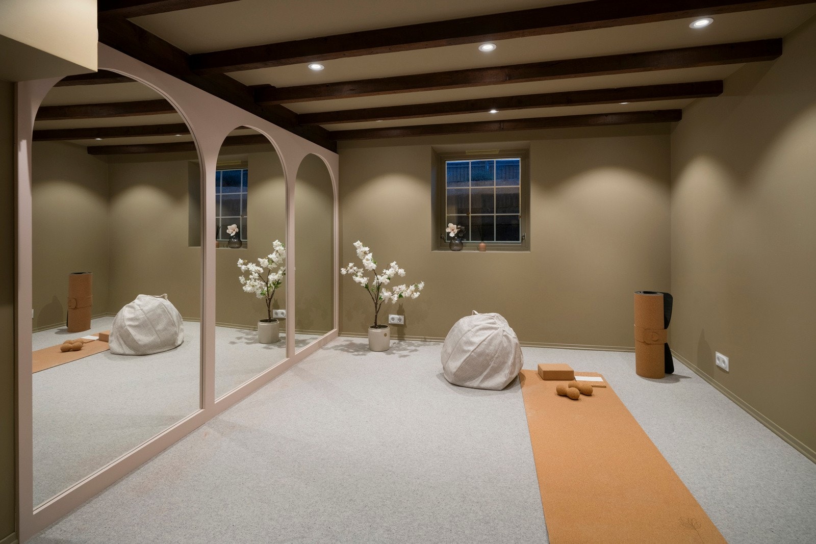 Yogarommet har teppe på gulvet, malte veggflater, synlige takbjelker, downlights og et vindu. Galleribilde