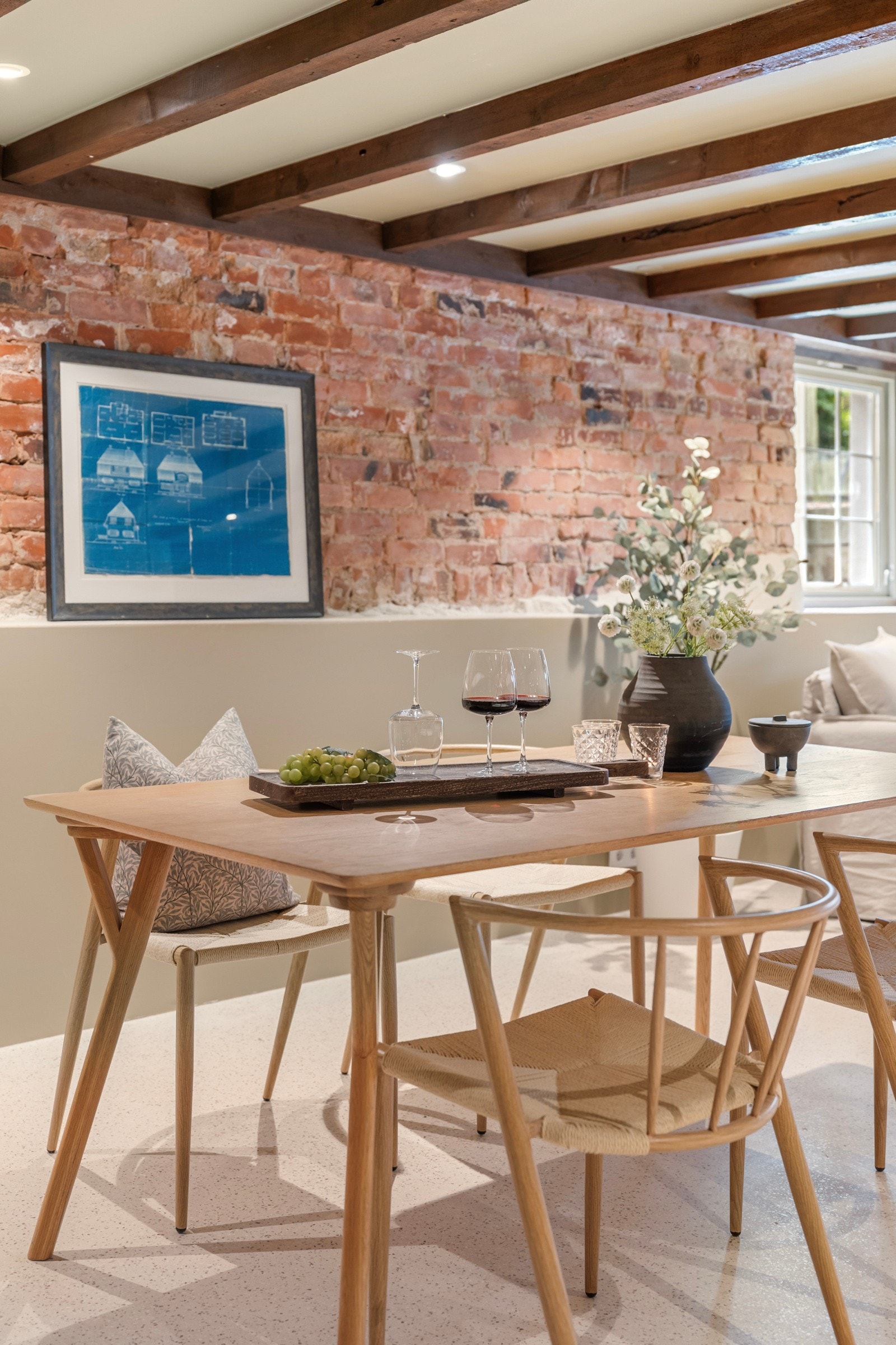 De glatte flatene brytes opp av mørke takbjelker og naken tegl langs deler av veggen mot hagen. Galleribilde