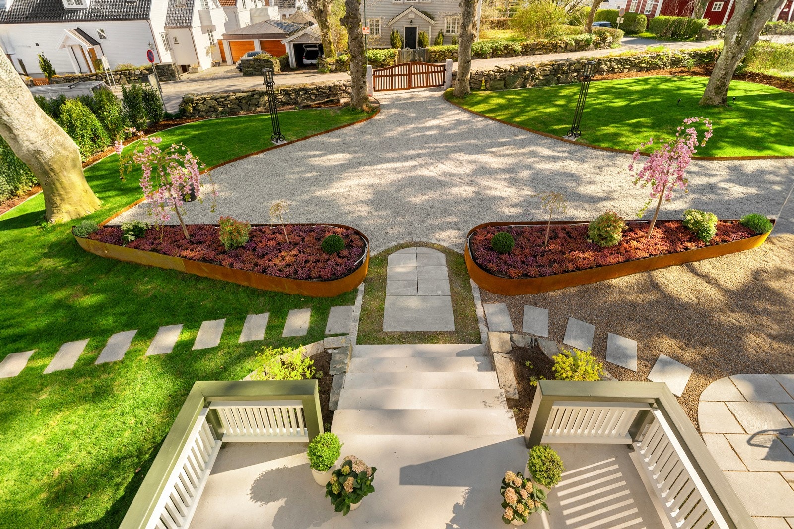 Den høye terrassen rammes inn av opphøyde bed i natursteinsmur, og i front markeres skillet mot gårdsplassen med store blomsterkasser i kortensstål. Galleribilde