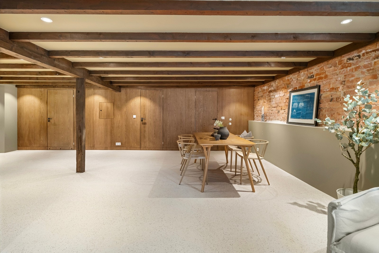 Kjellerstuen er stor og pent utført med lyst terrazzogulv, glatte, malte veggflater og listefri himling med downlights. Galleribilde