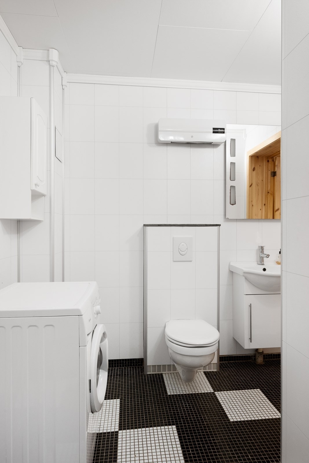 Rommet er enkelt innredet med servant og speil, vegghengt wc, samt opplegg for vaskemaskin. Galleribilde