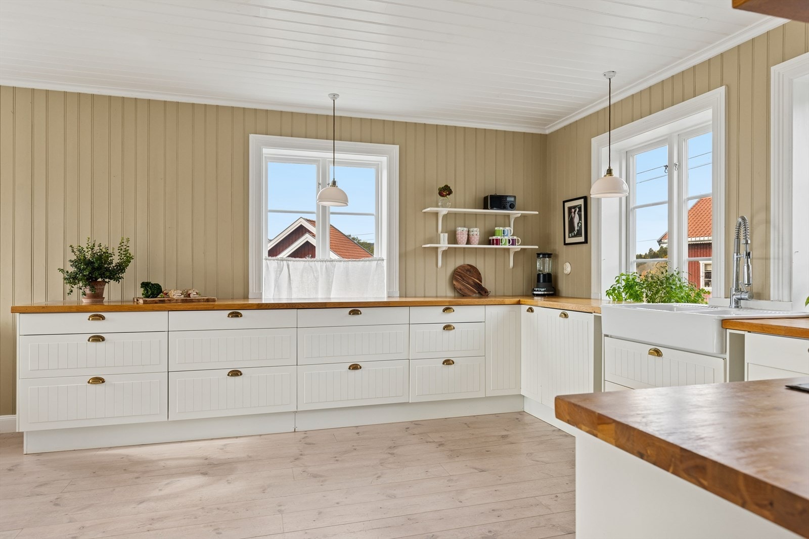 Innredning med lyse profilerte fronter, eik benkeplate og oppvaskbenk med to porselenskummer. Galleribilde