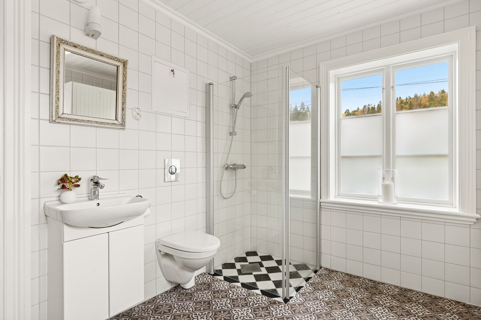 Flislagt baderom med behagelig gulvvarme. Badet er utstyrt med vegghengt toalett, dusjhjørne med glassvegger, samt baderomsinnredning med servant. Galleribilde