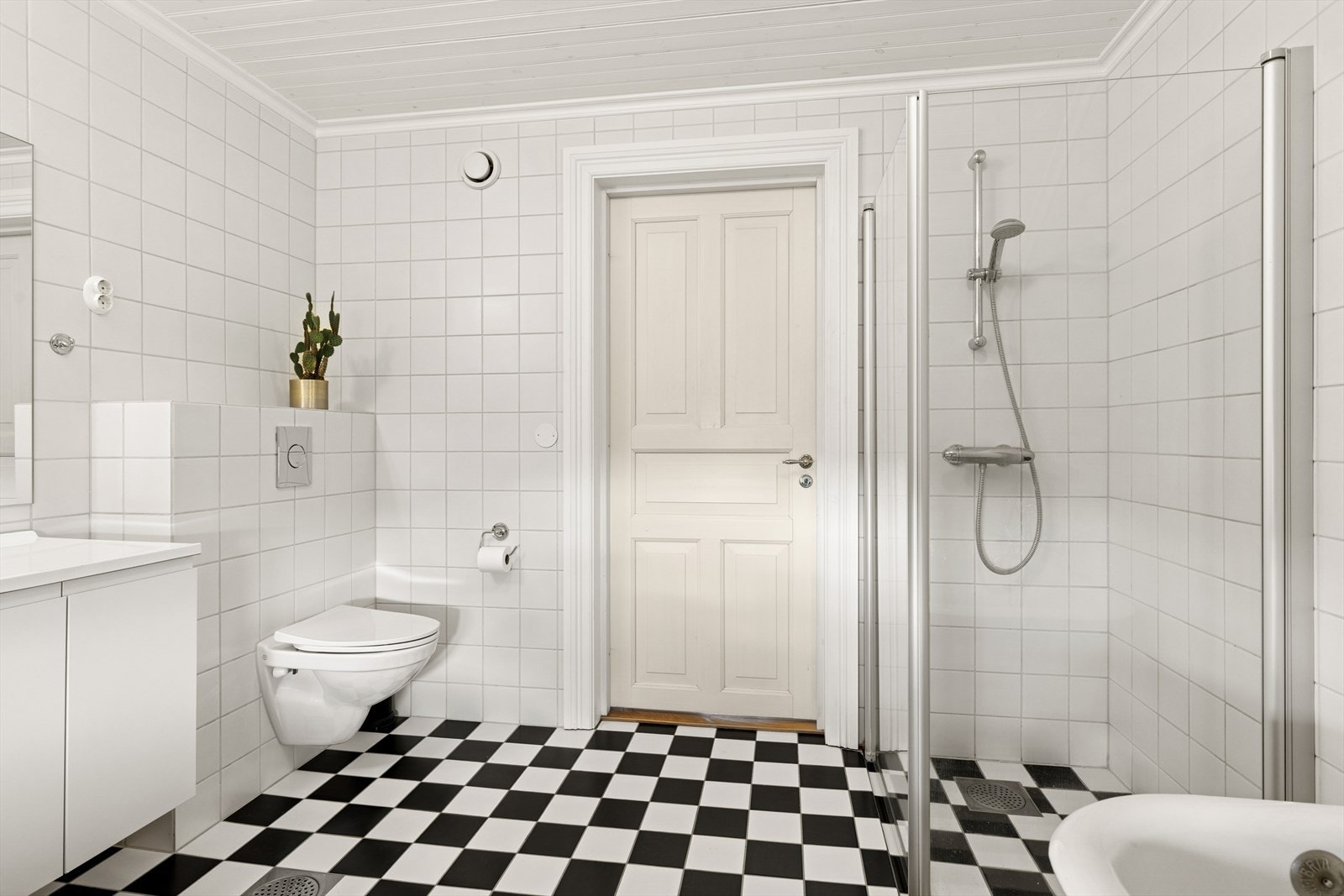 Badet er utstyrt med vegghengt toalett, badekar, dusjhjørnet med glassvegger og baderomsinnrendig med servant. Galleribilde